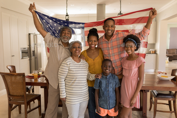 Portrait of multi-generation African American family holding an American flag at home