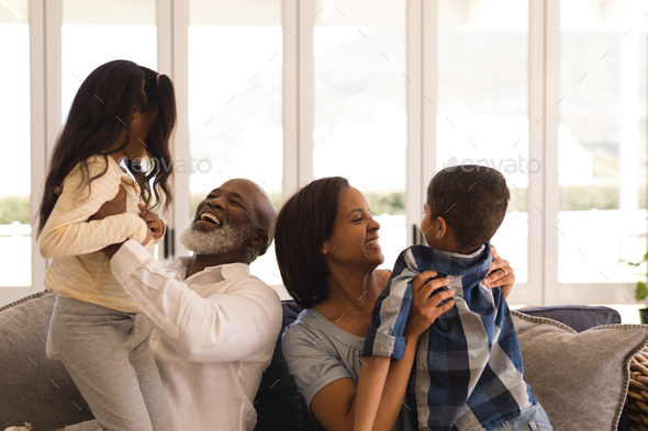 Front view of a happy multi-generation African American family having fun in living room at home