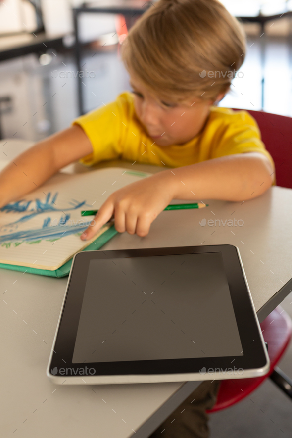 Boy Drawing Sketch On Notebook At Desk In A Classroom At