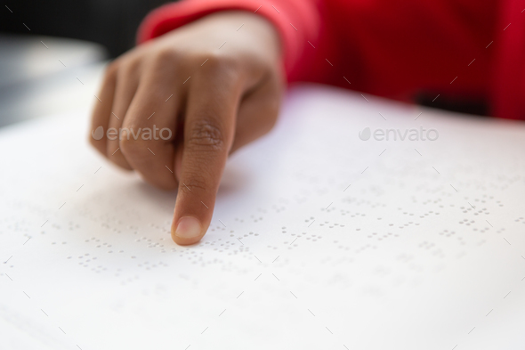 Close-up of blind mixed-race schoolboy hand reading a braille book in classroom at elementary school Close-up of blind mixed-race schoolboy hand reading a braille book in classroom at elementary school