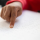 Close-up of blind mixed-race schoolboy hand reading a braille book in classroom at elementary school - $5.00 Close-up of blind mixed-race schoolboy hand reading a braille book in classroom at elementary school