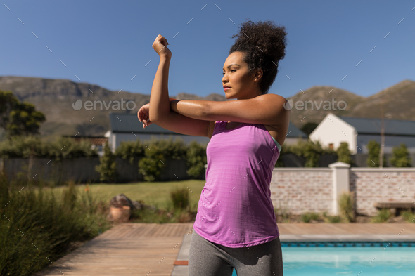 Woman performing stretching exercise next to the swimming pool in the backyard of home - Stock Photo - Images