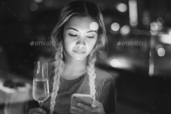 Serious young woman using a smartphone at a rooftop bar in the e