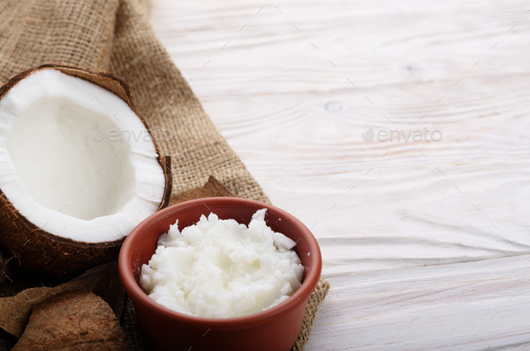 Coconut oil in brown clay bowl and shell with meat on hemp sackc - Stock Photo - Images