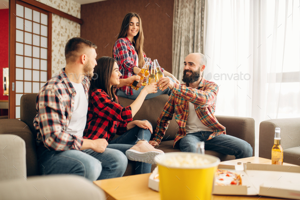 Friends clink bottles with beer at the home party - Stock Photo - Images