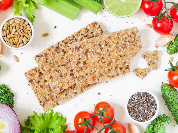 Top view of whole grain rye crispbreads surrounded by fresh vegetables - Stock Photo - Images