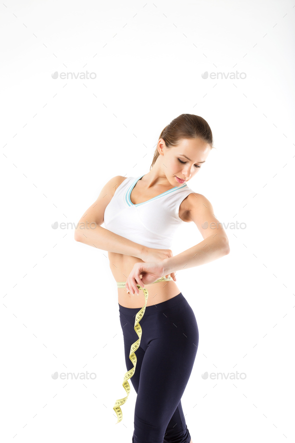 Sportswoman measuring her waist with a measure tape isolated on a