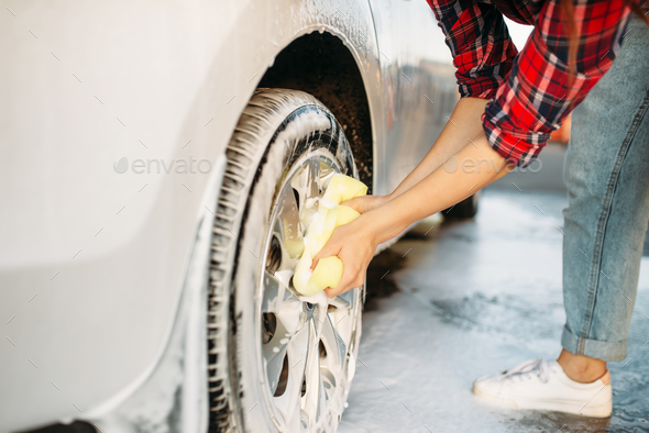 Cute woman scrubbing vehicle wheel with foam - Stock Photo - Images
