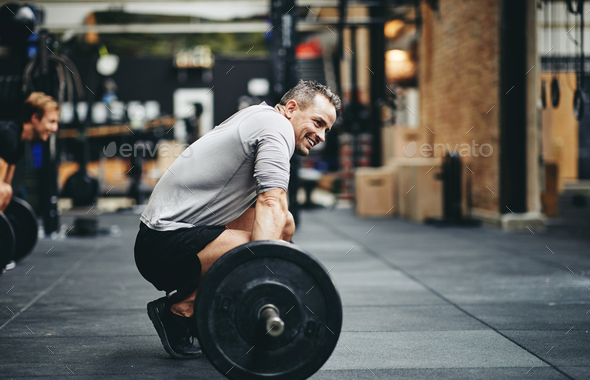Smiling man preparing to lift weights at the gym