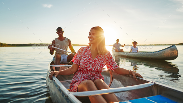 Smiling young woman canoeing with friends in the summer