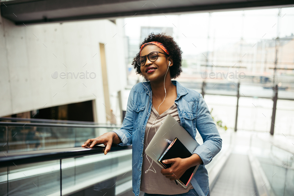 Young African female entrepreneur riding an escalator in an office