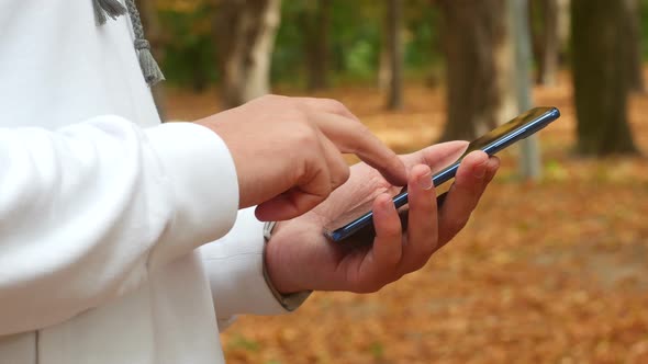 Man Uses A Smartphone In The Autumn In The Park