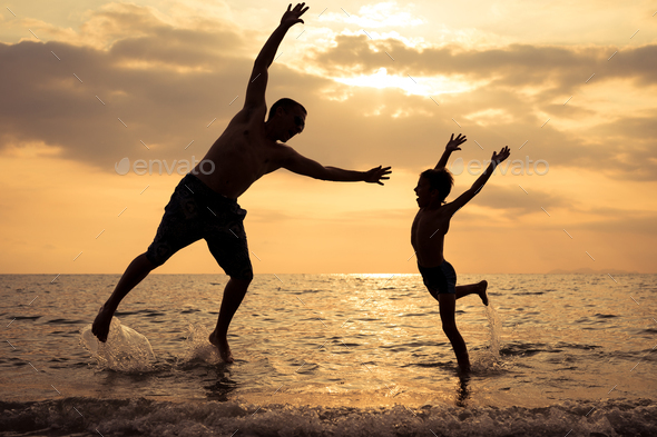 Father and son playing on the beach at the sunset time. - Stock Photo - Images