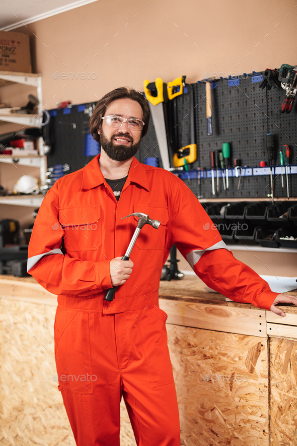 Smiling foreman in orange work clothes and protective eyewear ho
