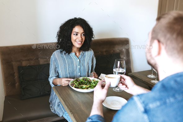 Young girl with dark curly hair have meeting with friend at cafe