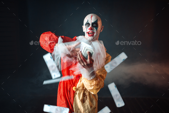 Bloody clown with crazy eyes holds fan of money