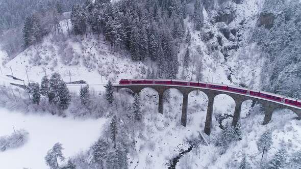 Viaduct and Train at Winter Day in Swiss Alps. Snowing. Switzerland. Aerial View alt