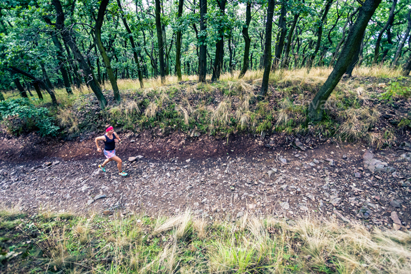 Trail running athletic woman in green forest, sports inspiration