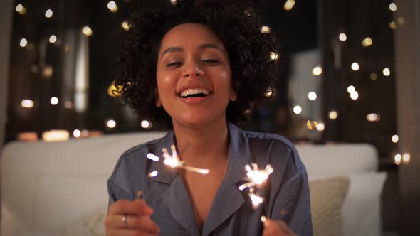 Happy Woman with Sparklers Sitting in Bed at Night