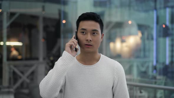 Middle Shot of Asian Male Talking on Phone While Walking