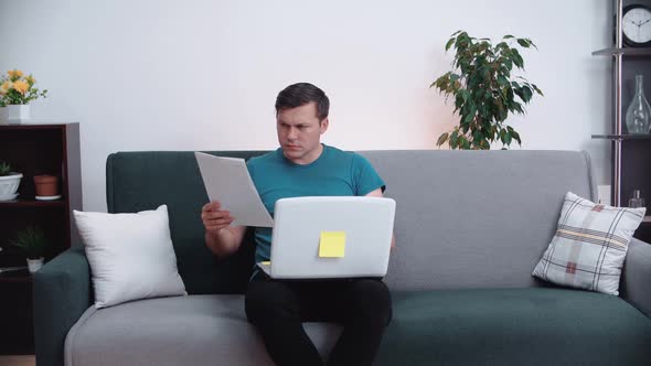 Young man reads documents while sitting on the couch