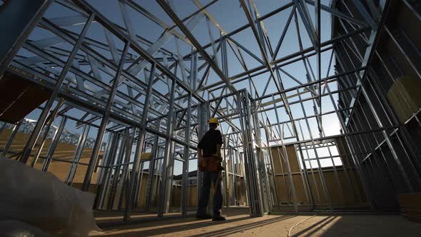 Steel Frame of the Building and Contractor Worker. The Construction Site. alt