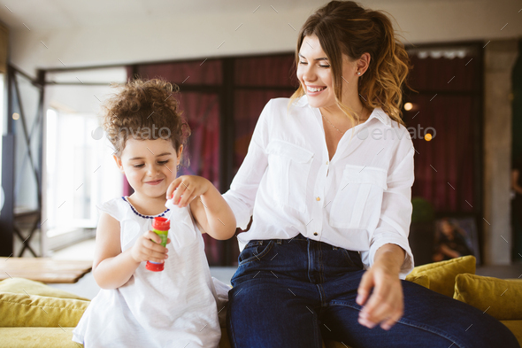 Young smiling mother in white shirt with little pretty daughter