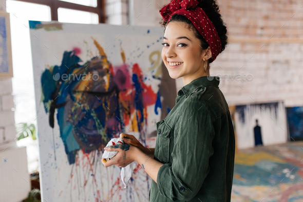 Young pretty smiling woman with dark curly hair drawing picture