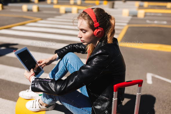 Beautiful girl in headphones listening music dreamily using tabl