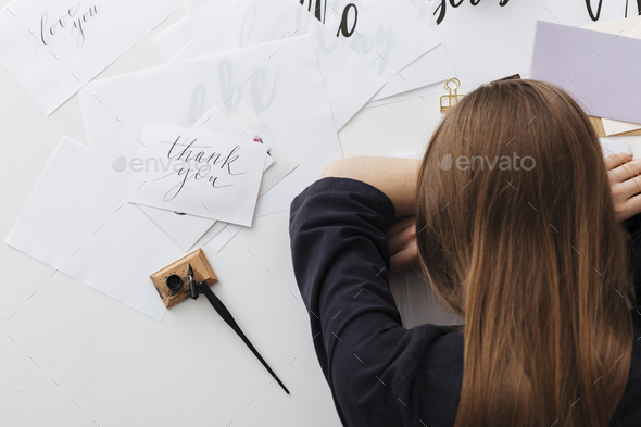 Photo of tired lady sitting and sleeping while leaning head on her hands at the white desk - Stock Photo - Images