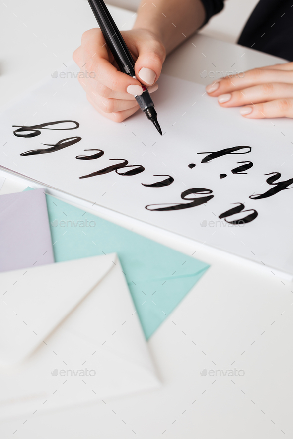 Close up photo of young woman hands writing alphabet on paper on desk isolated