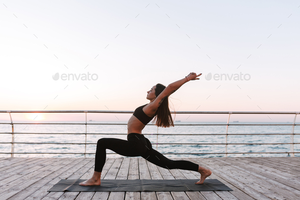 Fit woman doing yoga stretching exercise outdoor in beautiful mountains  landscape. Female on the rock with sea and sunrise or sunset background  training asans. Silhouette of woman in yoga poses 7567183 Stock