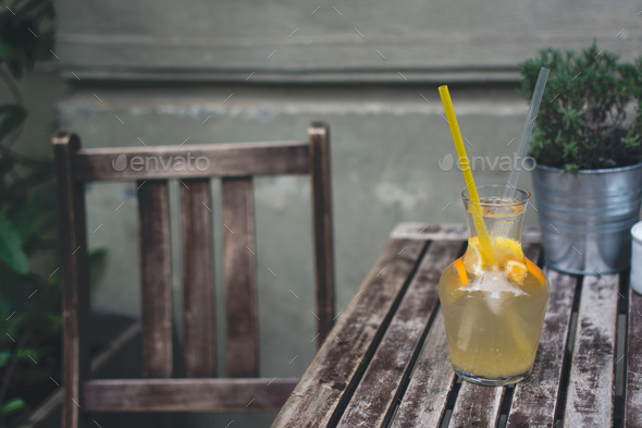 Cooling orange lemonade on a wooden desk outside