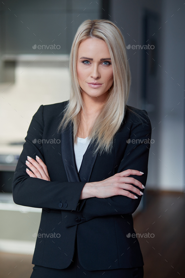 Nice and calm blond, middle age business woman standing at her office Stock  Photo by Daniel_Dash