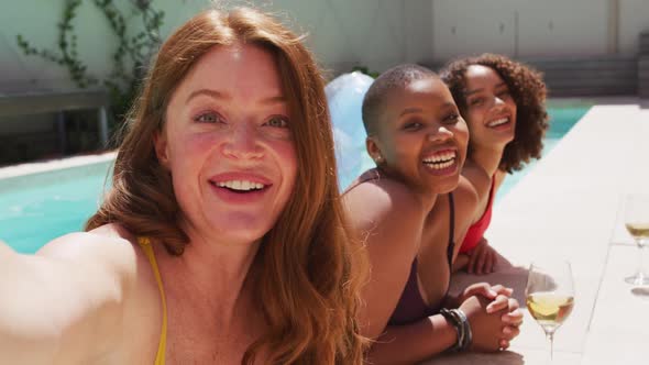 Diverse group of female friends having fun at pool taking selfie alt