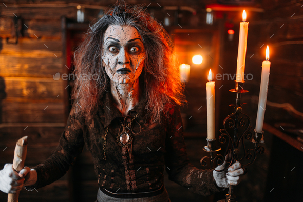 Scary witch with candlestick and cane reads spell - Stock Photo - Images