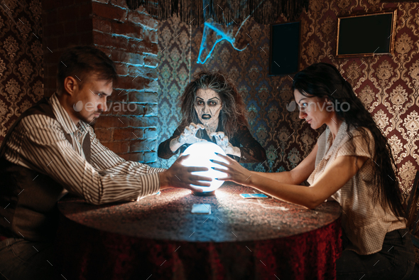 Foreteller calls the spirits over a crystal ball - Stock Photo - Images