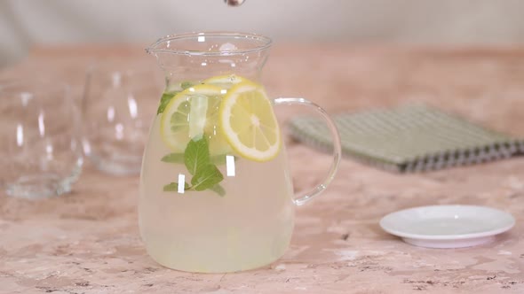 Female hands stirring a lemonade with spoon.