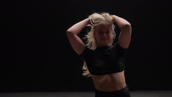 Alluring Young Woman Dancing in Studio Against Black Background alt