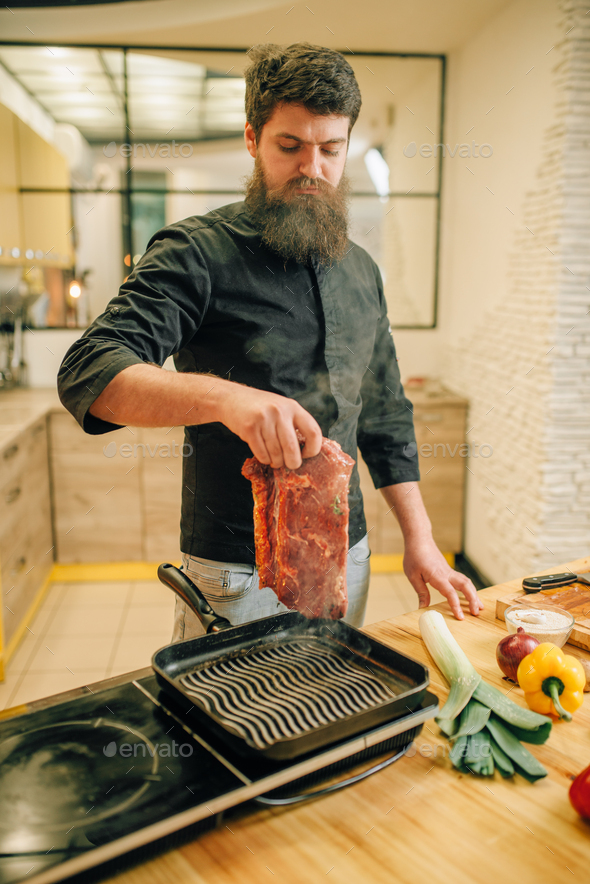 Bearded Chef Cooking Meat In A Pan On The Kitchen Stock Photo By