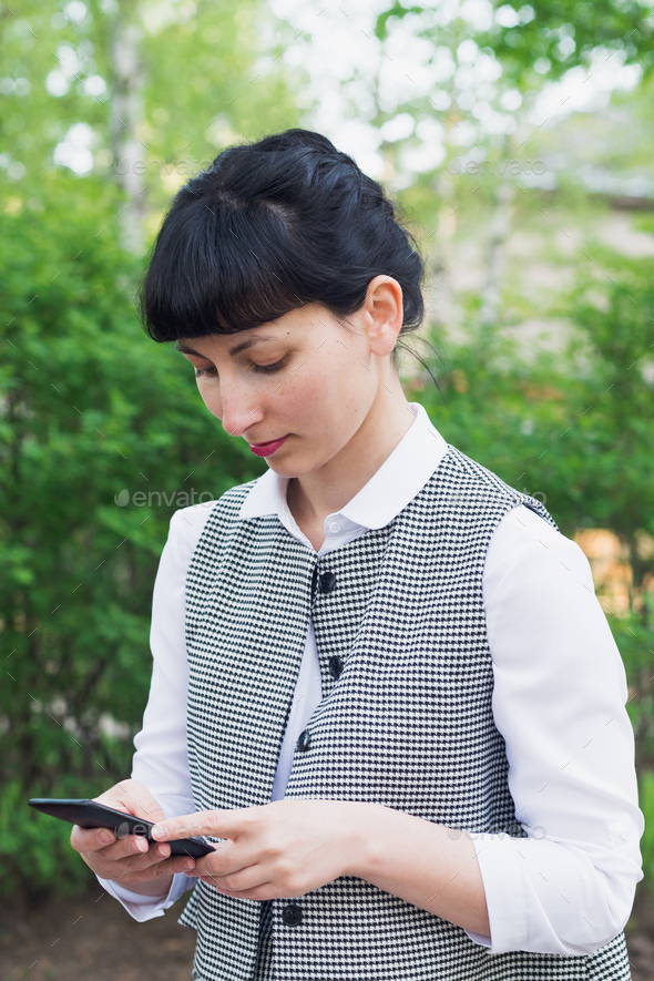 brunette caucasian businesswoman touch smartphone walking in park - Stock Photo - Images