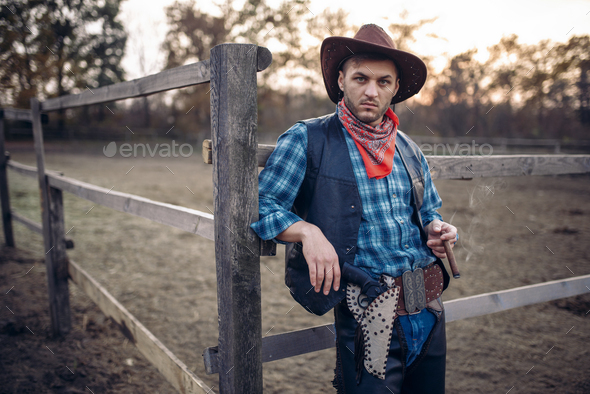Brutal cowboy poses in the horse corral on ranch