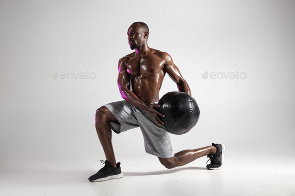 Young african-american bodybuilder training over grey background - Stock Photo - Images