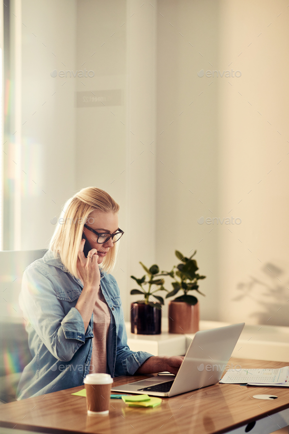 Focused young businesswoman talking on a cellphone in her office - Stock Photo - Images