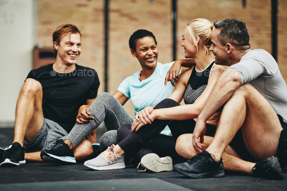 Smiling friends talking together on the floor of a gym