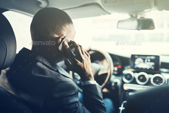 African businessman driving in the city talking on his cellphone - Stock Photo - Images