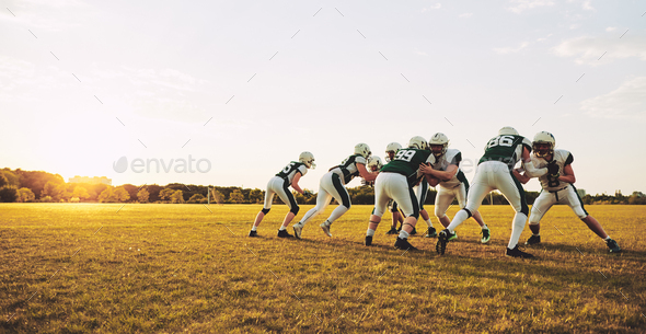 American football players doing practicing defense on a sports field