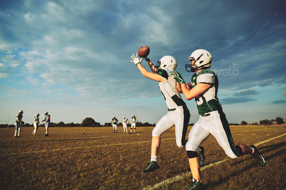 Young American football player making a reception during team practice
