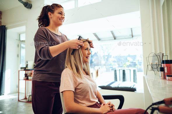 Smiling young woman discussing her hairstyle with a salon stylist Stock  Photo by FlamingoImages