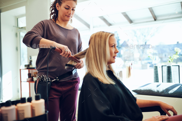 Hairdresser styling a client\'s hair in her hair salon